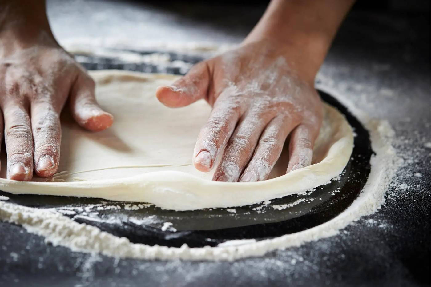 Carefully hand stretching pizza dough
